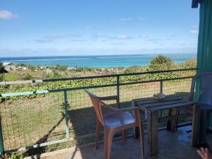 einen Tisch und Stühle auf einem Balkon mit Meerblick in der Unterkunft Petite maison de tôle Rodriguaises in Tambe