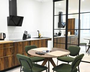 a kitchen with a table and green chairs in a room at Splendide Appartement haut de gamme hyper centre in Marmande +6 photos