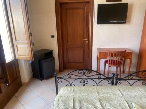 ein Schlafzimmer mit einem Bett und einem Tisch und einem Fernseher in der Unterkunft B&B Portaterra in Racale