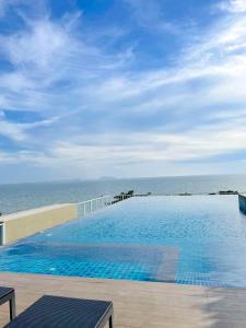 a large swimming pool with the ocean in the background at Sweetie's room & The Blu x Bangsaen in Ban Bang Saen (1)