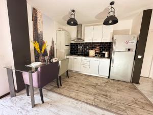 a kitchen with a table and a refrigerator at Vitamine Central Apartment in Craiova