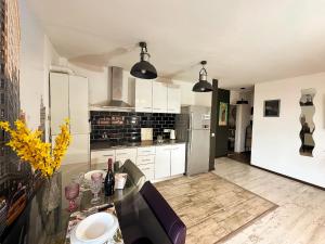 a kitchen with white cabinets and a table and a refrigerator at Vitamine Central Apartment in Craiova