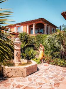 a woman walking past a fountain in front of a house at Domaine de l'Astragale in Saint-Tropez