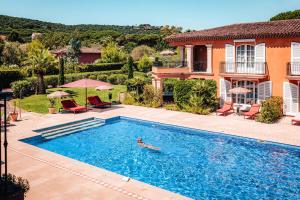 a person swimming in a swimming pool in front of a house at Domaine de l'Astragale in Saint-Tropez