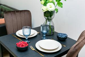 Una mesa negra con platos, vasos y flores. en Koszykowa 3 - Better Rental, en Varsovia
