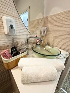 a bathroom with a sink with a mirror and towels at Vitamine Central Apartment in Craiova