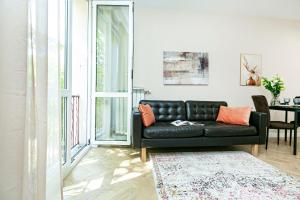 un sofá de cuero negro en una sala de estar con mesa en Koszykowa 3 - Better Rental, en Varsovia