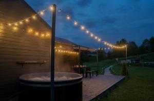 bañera de hidromasaje en una terraza de madera con luces en KASZUBSKA BALIA DOMEK z BALIĄ NA WYŁĄCZNOŚĆ, en Połęczyno