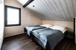 2 camas en una habitación con paredes de madera y ventana en Syöte Ski Villa, en Syöte