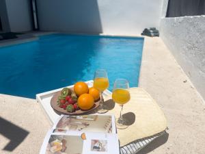 a plate of fruit and wine glasses next to a swimming pool at RosaritoHomes in Madrigal de la Vera