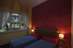 una camera con due letti e una parete rossa di B&B Sant'Agostino a Milano