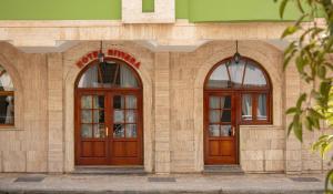 a building with two wooden doors and two windows at Riviera Hotel-City Center in Vlorë