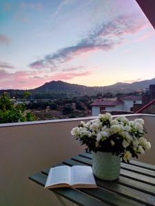 an open book on a table with a vase of flowers at Sa Paxi Arbus in Arbus