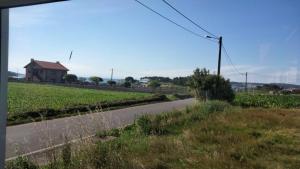 an empty road next to a field with a house at Pensión Atlántico in Muxia