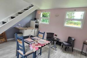 a dining room with a table and chairs and a staircase at Le gîte des Allains in Sainte-Suzanne-en-Bauptois