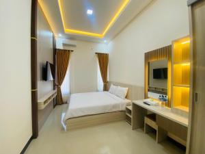 a hotel room with a bed and a television at Kanggo Riko Family Homestay Mitra Reddoorz in Banyuwangi