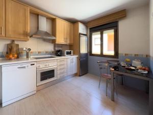 une cuisine avec des appareils blancs et une table avec des chaises dans l'établissement VillaHomes, à Villanueva de la Vera 22 autres photos