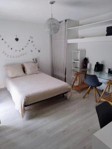 a white bedroom with a bed and a desk at Chez Paul et Mélusine in Périgueux