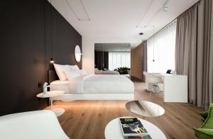 - une chambre avec un grand lit blanc et un bureau dans l'établissement KPM Hotel & Residences, à Berlin
