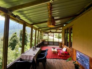a dining room with a table and chairs and windows at Tirthan Ecostay in Gushaini