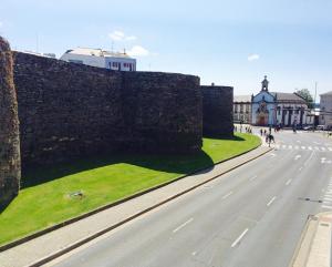 an empty road next to a stone wall and a building at Apartment Lugo Rooms in Lugo