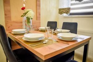 a wooden table with plates and glasses and a vase of flowers at Domek Pod Brzyzkiem in Białka Tatrzanska