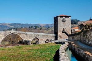 ein großes Steingebäude mit einer Brücke und einem Fluss in der Unterkunft casa dos Ferreira no Douro in Ucanha