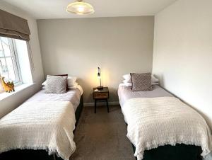 Dos camas en una habitación con una lámpara sobre una mesa. en Walker House, en Gloucestershire 5 fotos más