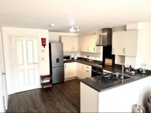Una cocina con gabinetes blancos y una encimera negra. en Walker House, en Gloucestershire