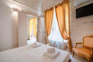 アルベロベッロにあるTrulli Contento - Rooms & Apartmentsのベッドと椅子と窓のある寝室