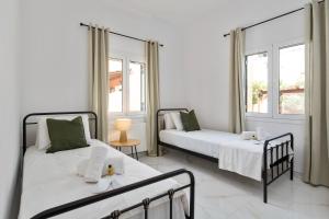 two beds in a white room with two windows at Maximos House in Corfu Town +34 photos