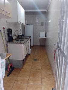 une petite cuisine avec des appareils blancs et un sol carrelé dans l'établissement Coração da Ocian, à Praia Grande