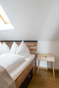 a bed with white sheets and a night stand next to a table at FarawayHomes Studio Graz #6 in Graz