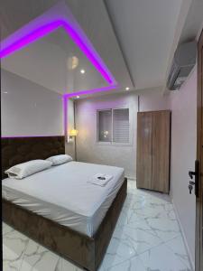 una camera da letto con un grande letto con illuminazione viola di appartement riad sofia a Martil
