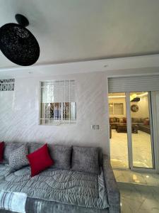 un soggiorno con divano grigio e cuscini rossi di appartement riad sofia a Martil