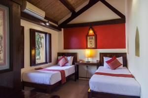 two beds in a room with red walls at Rikitikitavi in Kampot
