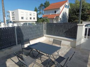 einen Tisch und Stühle auf einer Terrasse mit einem Zaun in der Unterkunft plain pied proche de la plage in Saint-Georges-de-Didonne + 1 Foto