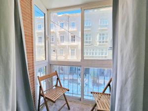 ein Balkon mit zwei Stühlen und einem großen Fenster in der Unterkunft Apartamentos Nuevo Edificio Alba Cartagena centro Parking in Cartagena