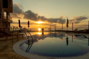 a swimming pool with a sunset in the background at Swan Bay complex in Chernomorets