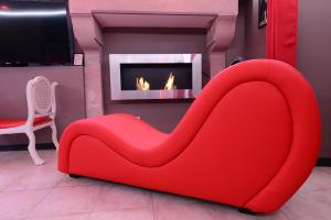 a red couch in a living room with a fireplace at Love Room "Les Secrets de Winna" in Augé