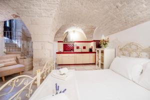 アルベロベッロにあるTrulli Contento - Rooms & Apartmentsの白いベッドとキッチンのある寝室 +32枚の写真