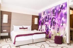 um quarto com uma cama com um quadro roxo na parede em Ambient Hotel & Aroma Spa em Sikonda