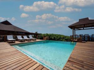 a pool on a deck with chairs and a gazebo at Aloha 22 in Ponta Mamoli