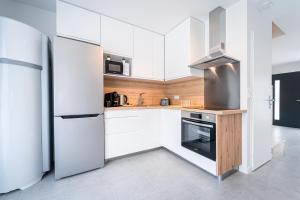 a white kitchen with white cabinets and a refrigerator at Le Cool Plex Duplex avec Jardin, Disney 10mn in Esbly