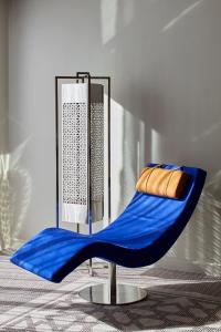 a blue chair sitting in a room with a mirror at Mövenpick Hotel Mansour Eddahbi Marrakech in Marrakech