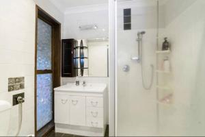 a white bathroom with a shower and a sink at Hopoe City Villa in Rotorua