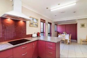 a kitchen with red cabinets and a counter top at Hopoe City Villa in Rotorua