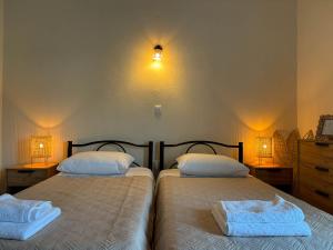 two beds in a bedroom with two lamps on the wall at Kassiopi Bella Vista in Kassiopi