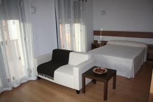 een slaapkamer met een bed, een stoel en een tafel bij Alojamiento Ubaldo Nieto in Carracedo del Monasterio