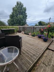 une terrasse en bois avec une table, des chaises et des fleurs dans l'établissement Single room with beautiful garden, à Édimbourg